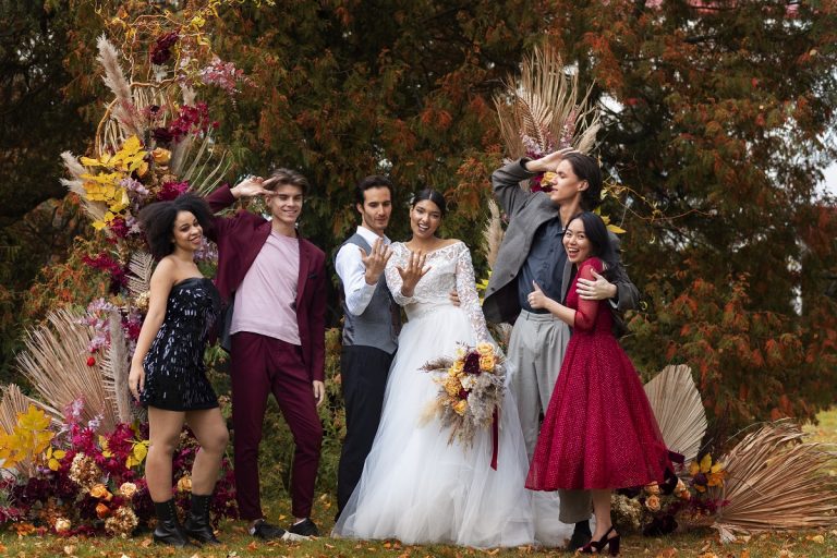 bride and groom posing with guests amidst fall foliage at their wedding