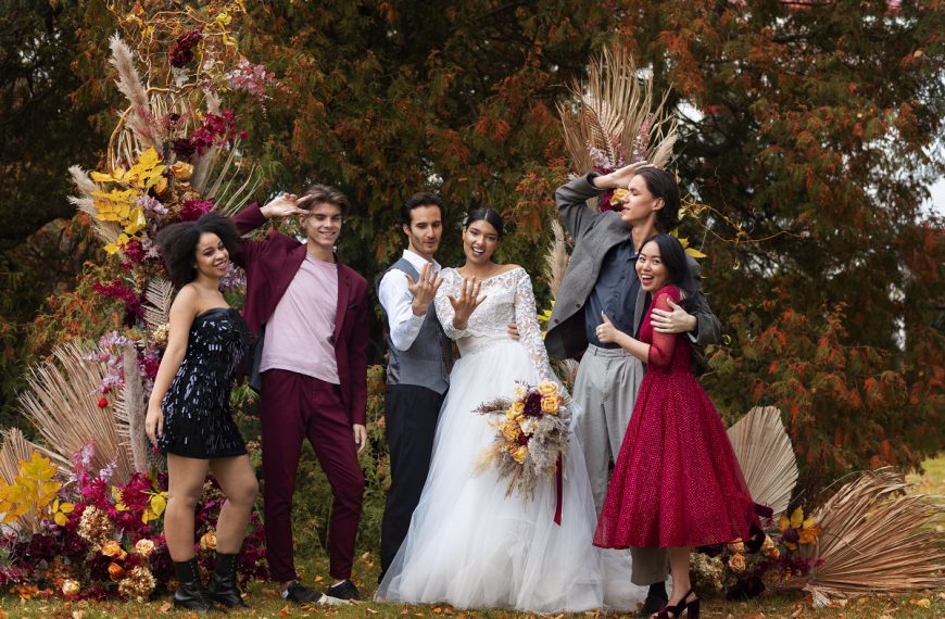 bride and groom posing with guests amidst fall foliage at their wedding