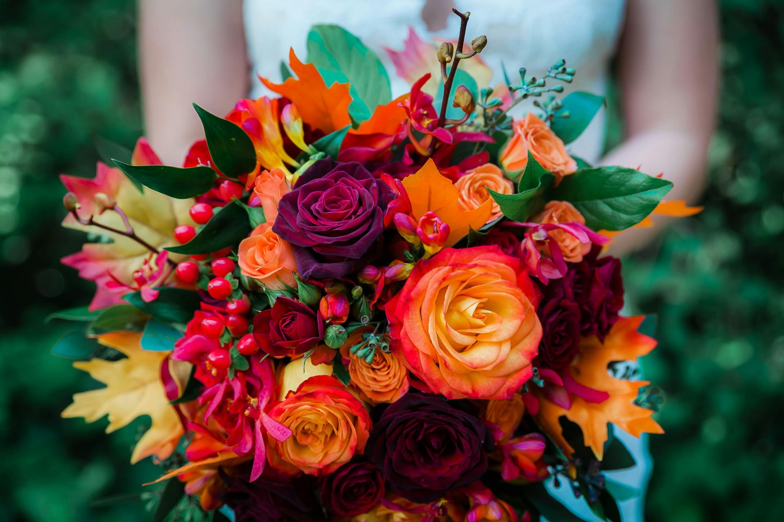 bride holding a vibrant bouquet of fall flowers